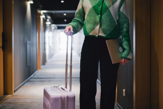 person som står i en hotellkorridor med en resväska